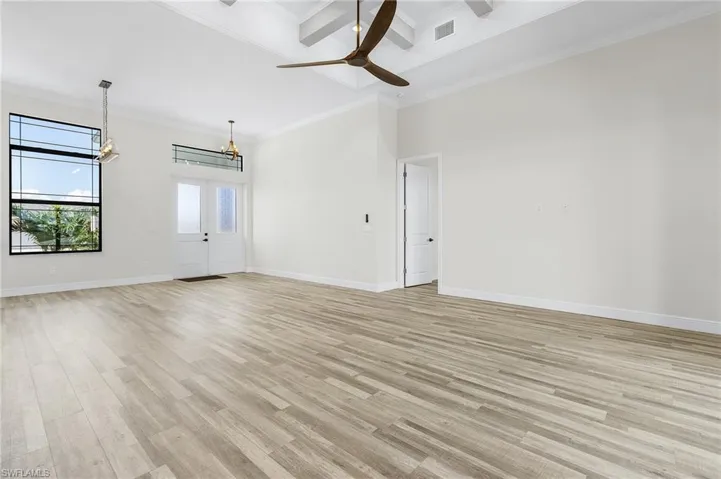 Unfurnished room with light hardwood / wood-style flooring, beam ceiling, ceiling fan with notable chandelier, and crown molding