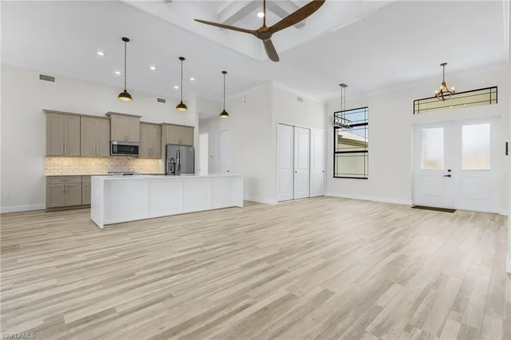 Kitchen featuring gray cabinetry, light hardwood / wood-style floors, stainless steel appliances, and pendant lighting