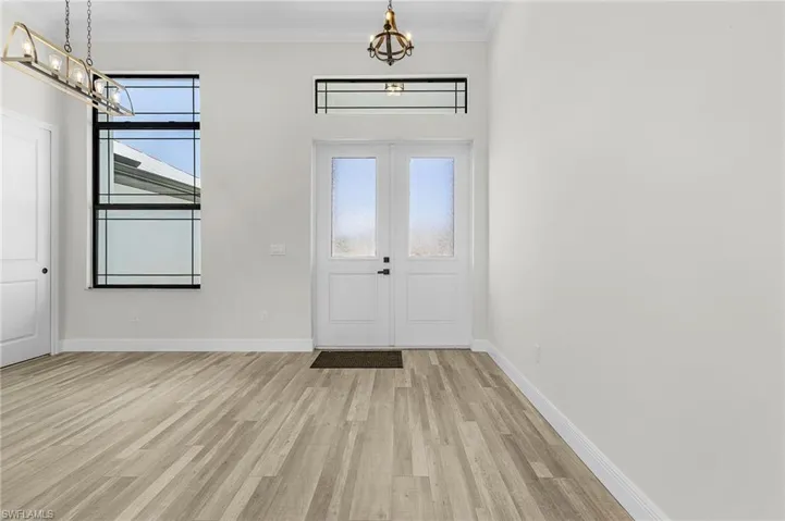 Foyer entrance featuring crown molding, a wealth of natural light, and light wood-type flooring