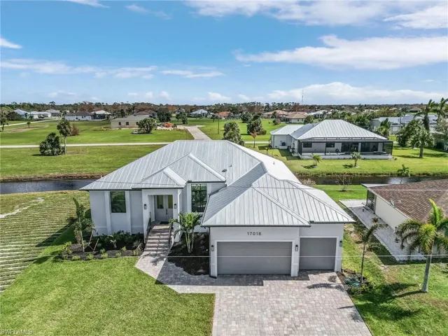 View of front of house featuring a garage, a front lawn, and a water view