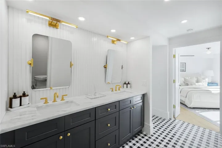 Ensuite bathroom with double vanity, recessed lighting, and light tile patterned floors