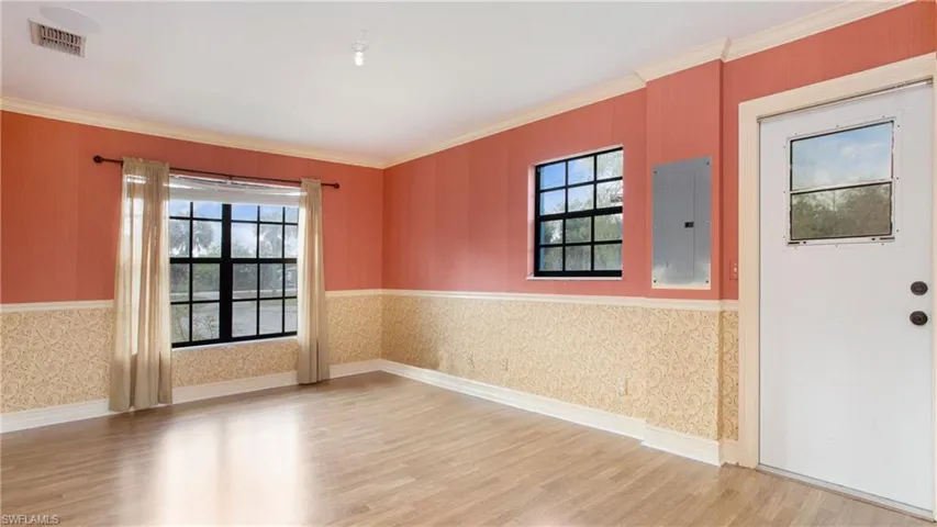 Bedroom 2 featuring light colored laminate flooring, chair rail and crown molding