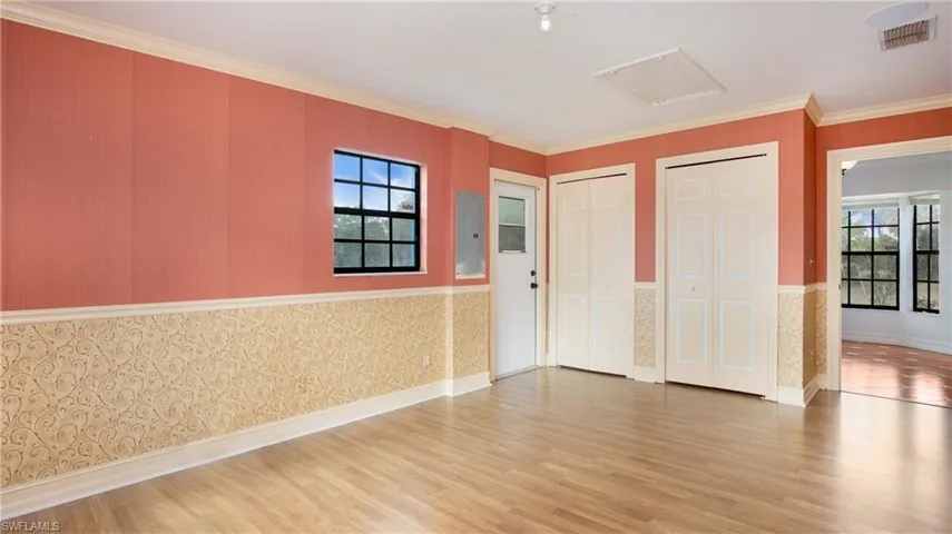 Bedroom 2 featuring light colored laminate flooring, crown molding, chair rail and large closet