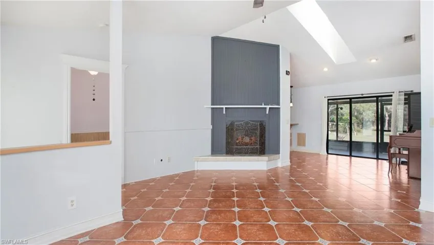 Living room featuring patterned tile flooring, vaulted ceiling, fireplace and ceiling fan