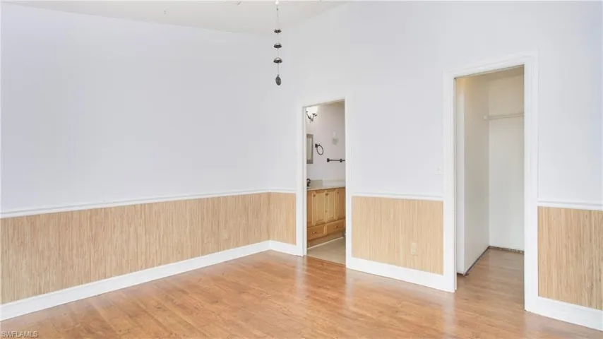 Master bedroom featuring light colored laminate flooring, chair rail and vaulted ceiling
