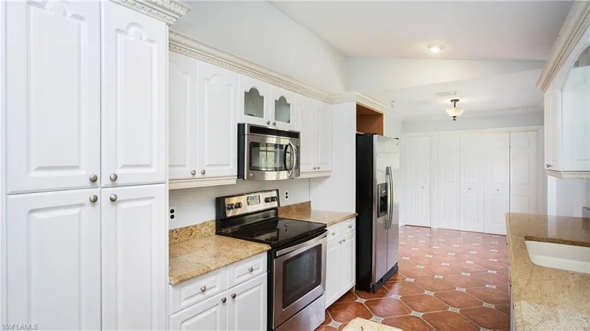 Kitchen featuring white cabinetry, granite counters, vaulted ceiling and appliances with stainless steel finishes