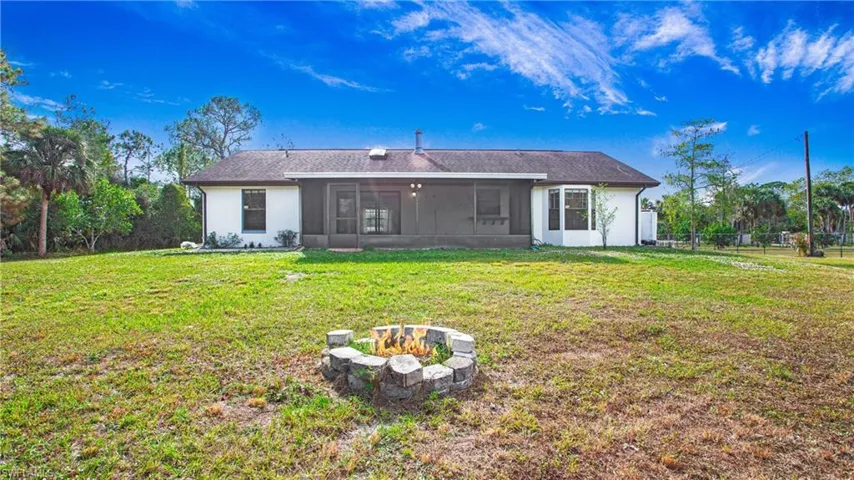 Back of house featuring the covered lanai and fire pit