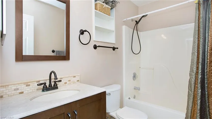 Full guest bathroom with shower/bath combination, vanity, tasteful backsplash and toilet