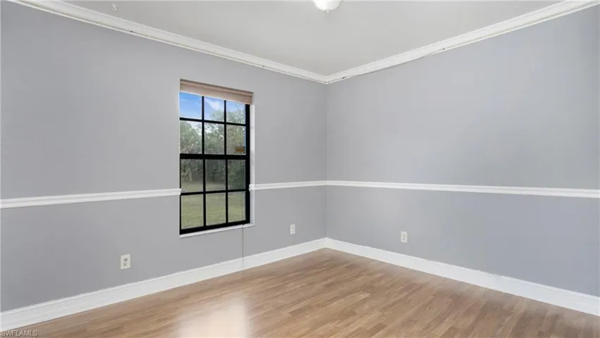 Bedroom 4 featuring light colored laminate flooring, chair rail and crown molding
