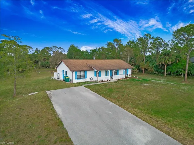 Ranch-style house featuring covered porch, paved driveway and front yard