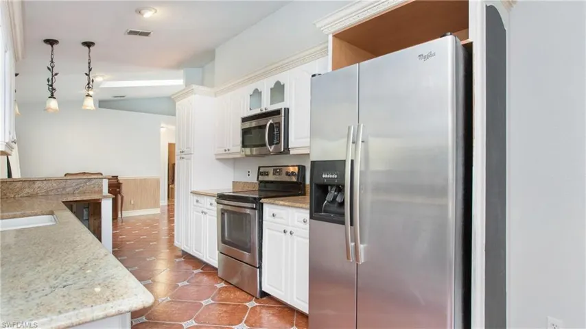 Kitchen featuring pendant lighting, white cabinets, appliances with stainless steel finishes and granite counters