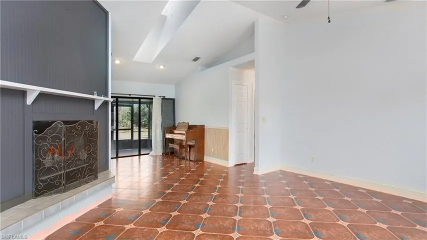 Living room featuring patterned tile flooring, skylight, ceiling fan and vaulted ceiling