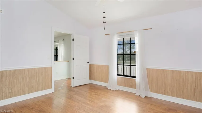 Master bedroom with vaulted ceiling, chair rail and light colored laminate flooring