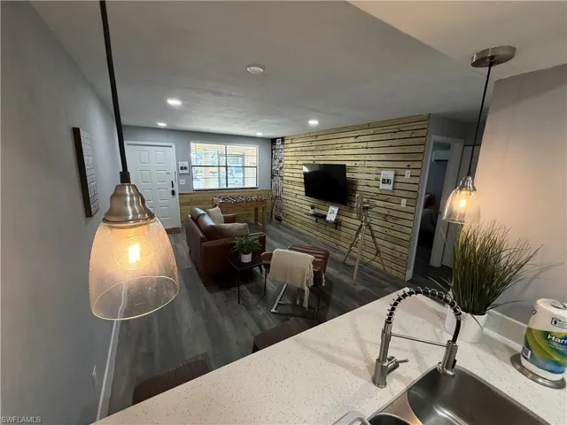 Living area featuring dark wood finished floors, wood walls, recessed lighting, and a wood stove