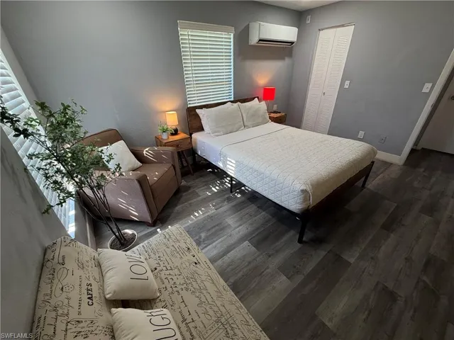 Bedroom with a wall mounted mini split, a closet, and dark wood finished floors