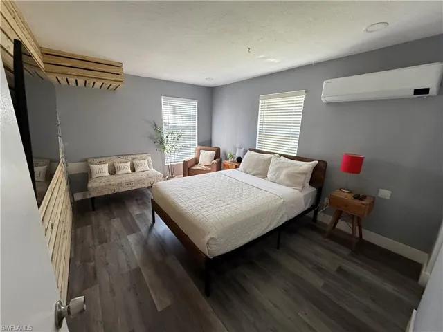 Bedroom with dark wood finished floors and a wall mounted mini split