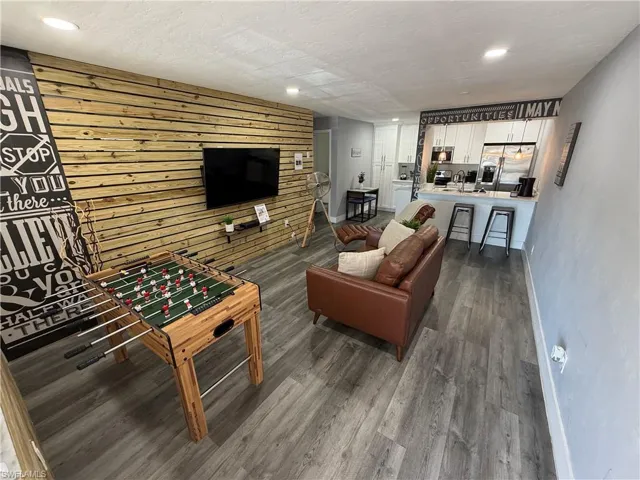 Living area featuring wood walls, dark wood-type flooring, an accent wall, recessed lighting, and a textured ceiling