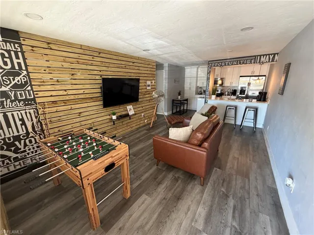 Living room with dark wood finished floors, a textured ceiling, and wood walls
