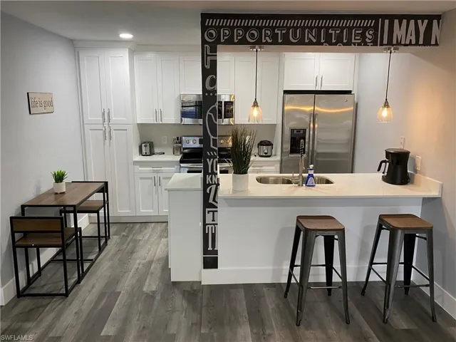 Kitchen with a peninsula, stainless steel appliances, white cabinetry, and a breakfast bar