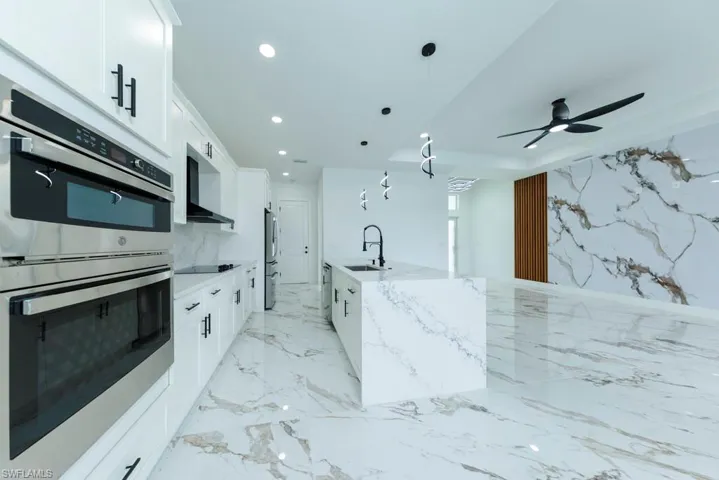 Kitchen with appliances with stainless steel finishes, decorative light fixtures, light stone countertops, white cabinetry, and recessed lighting