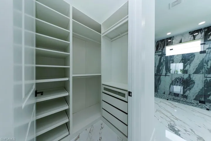 Walk in closet featuring light marble finish floors
