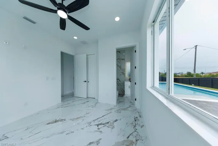 Unfurnished bedroom with light marble finish floors, recessed lighting, connected bathroom, a ceiling fan, and a closet