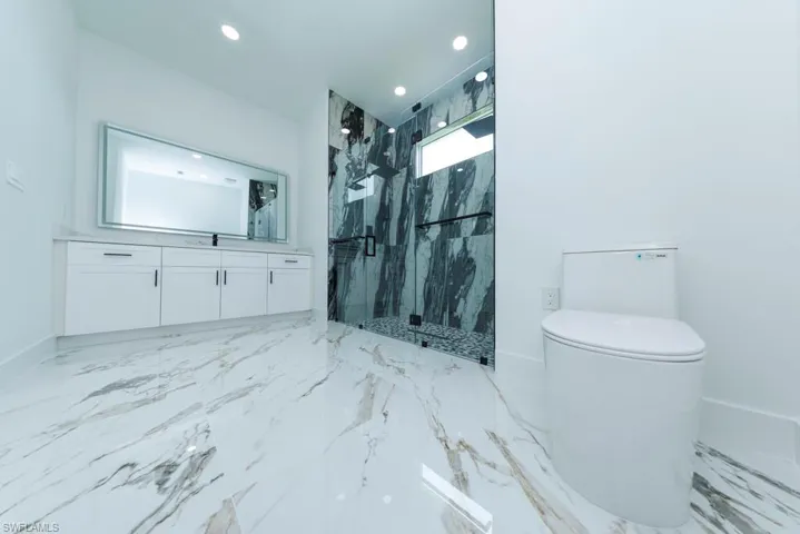 Full bathroom with a marble finish shower, vanity, light marble finish floors, and recessed lighting