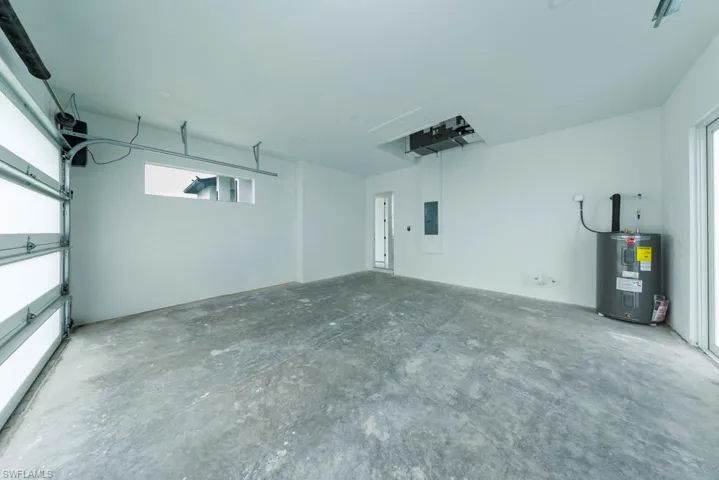 Garage featuring electric water heater and electric panel