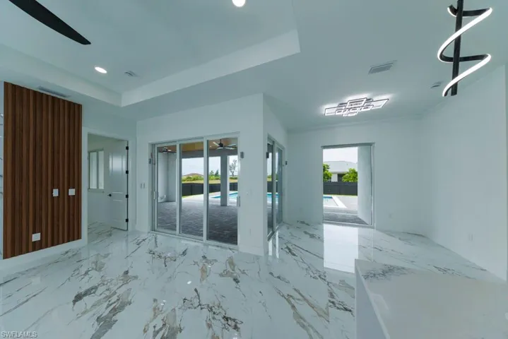 Spare room with a ceiling fan, light marble finish flooring, healthy amount of natural light, a raised ceiling, and recessed lighting