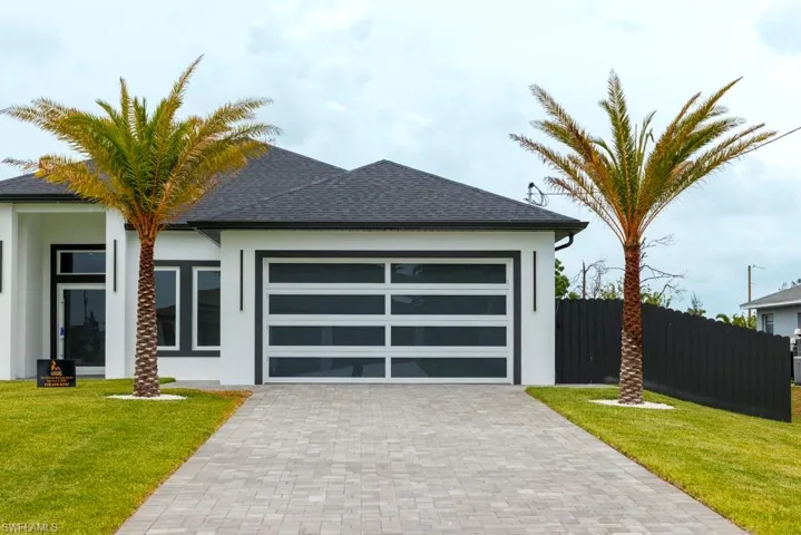 View of front of property with stucco siding, decorative driveway, a garage, and roof with shingles