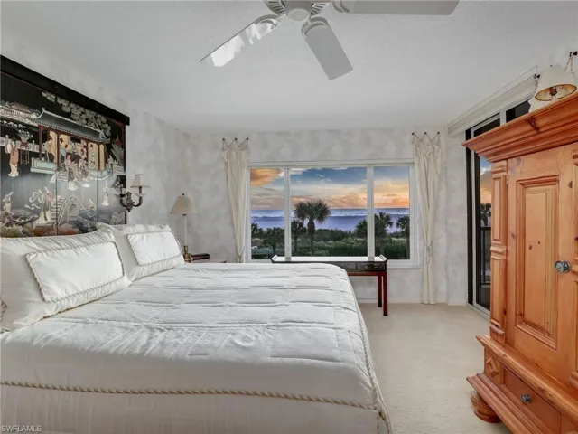 Bedroom with a textured ceiling, light colored carpet, and ceiling fan