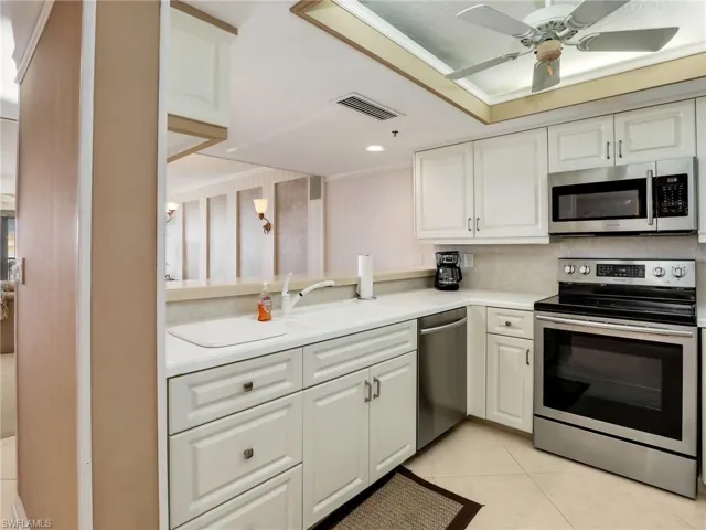 Kitchen featuring white cabinets, ceiling fan, light tile patterned floors, sink, and stainless steel appliances