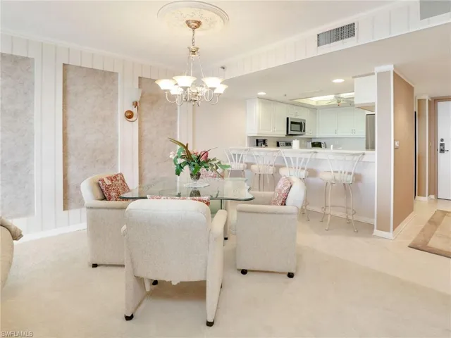 Dining room with an inviting chandelier, light carpet, and ornamental molding