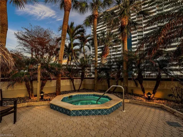 Pool at dusk with a hot tub and a patio area