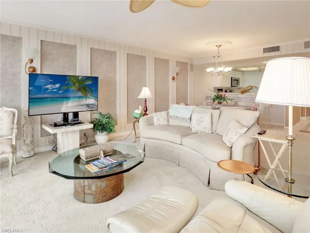 Carpeted living room with crown molding and a notable chandelier