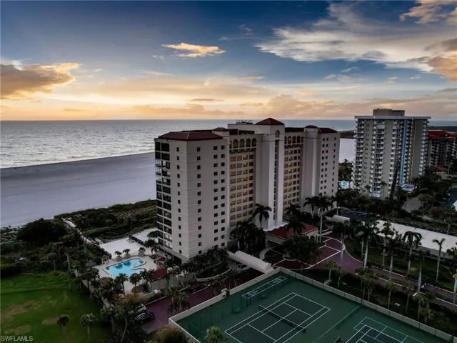 Aerial view at dusk featuring a water view and a view of the beach