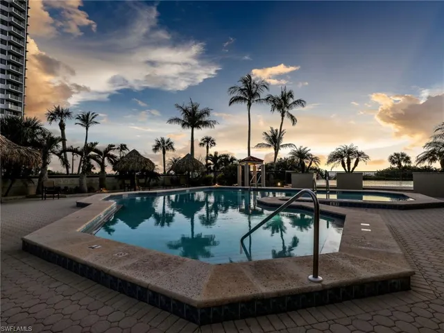 Pool at dusk with a patio and a hot tub