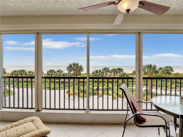 Sunroom / solarium with a beach view, a water view, and ceiling fan