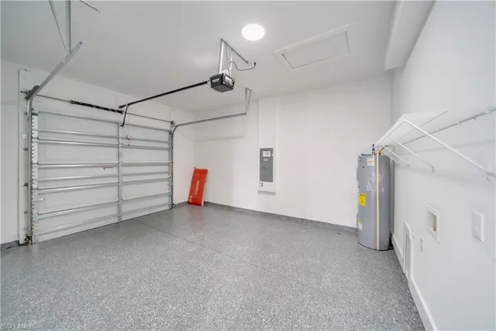 Garage with water heater, a garage door opener, and electric panel