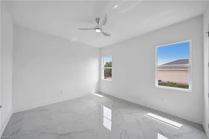 Spare room featuring marble finish flooring, baseboards, and a ceiling fan