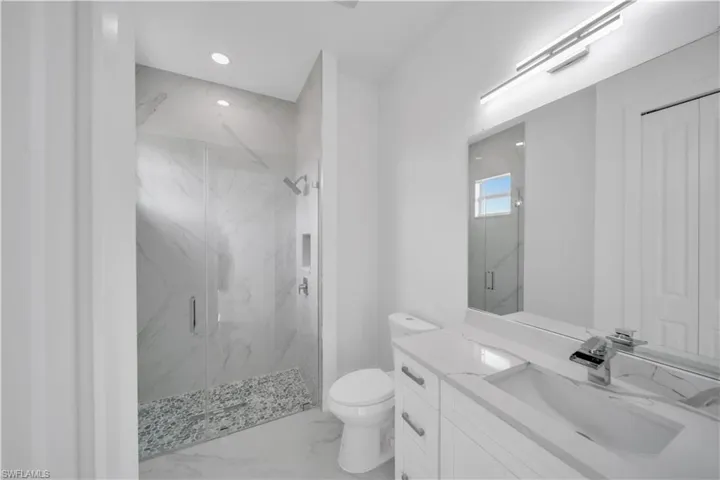 Full bath featuring a marble finish shower, toilet, marble look tile flooring, vanity, and recessed lighting