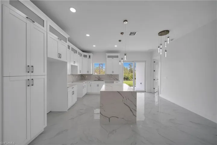 Kitchen featuring a sink, light marble finish floors, glass insert cabinets, light stone countertops, and recessed lighting