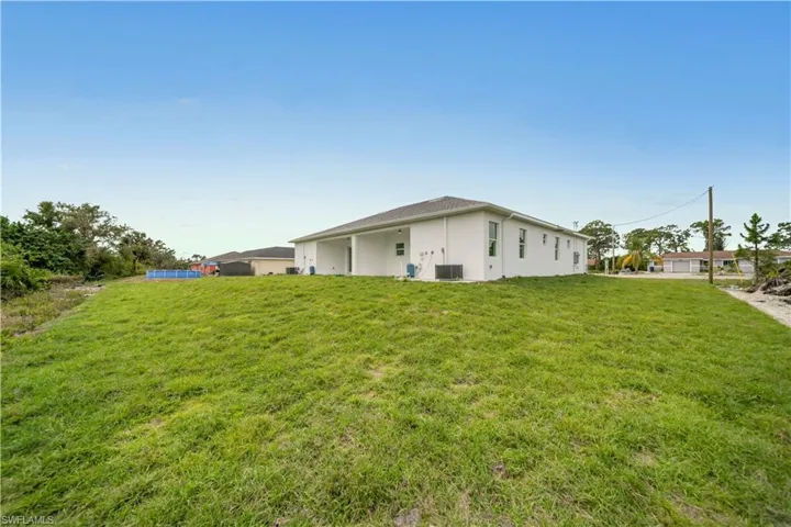 View of side of home featuring central AC, a lawn, and stucco siding