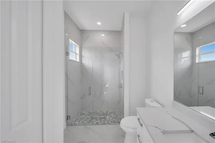 Full bathroom featuring a marble finish shower, vanity, marble finish floors, and recessed lighting
