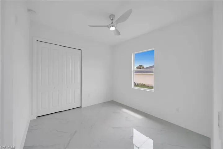 Unfurnished bedroom with light marble finish flooring, a closet, and ceiling fan