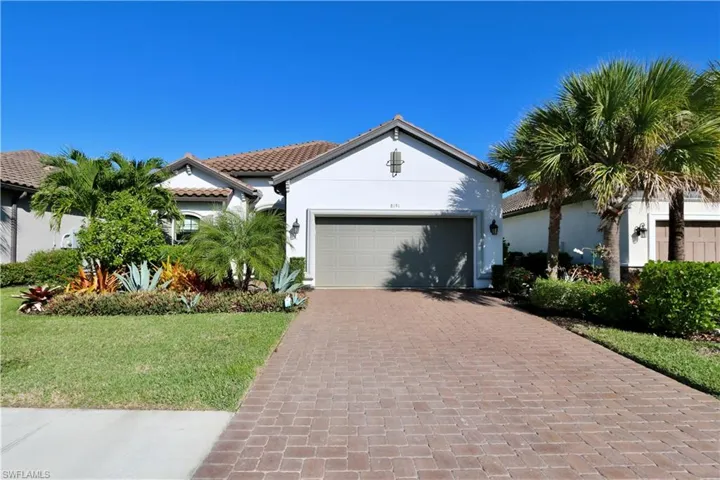 Mediterranean / spanish home with stucco siding, an attached garage, driveway, a front lawn, and a tiled roof