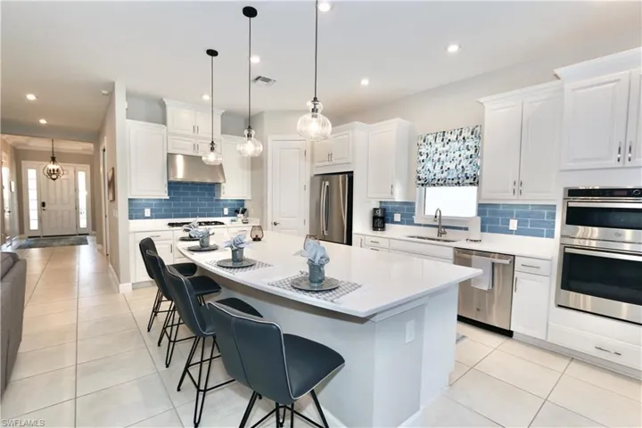 Kitchen featuring stainless steel appliances, white cabinetry, a kitchen breakfast bar, and light tile patterned floors