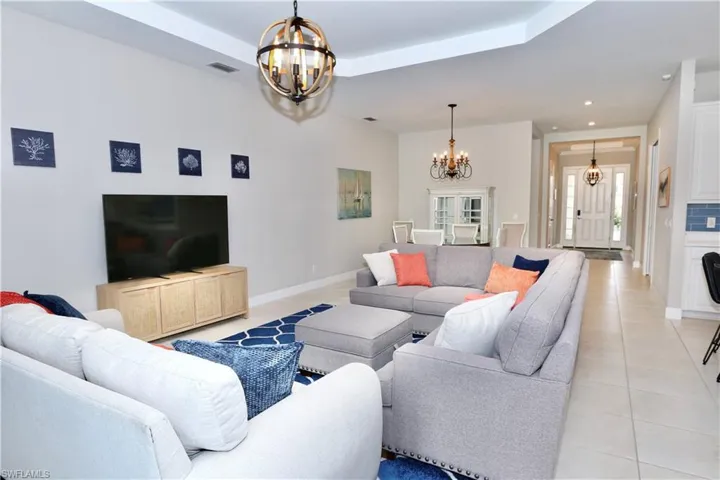 Living area featuring hanging lights, light tile patterned floors, and a raised ceiling