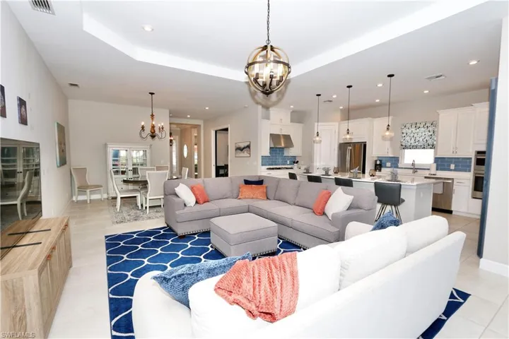 Living area featuring a chandelier, a tray ceiling, and light tile patterned flooring