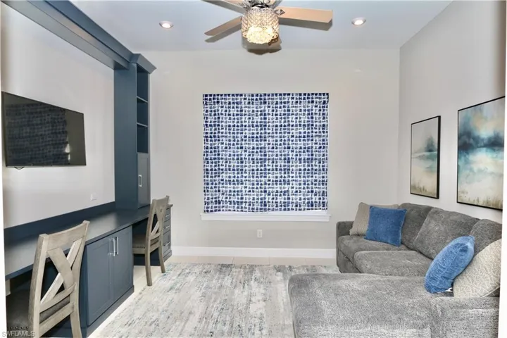 Living room with built in desk, ceiling fan, and recessed lighting